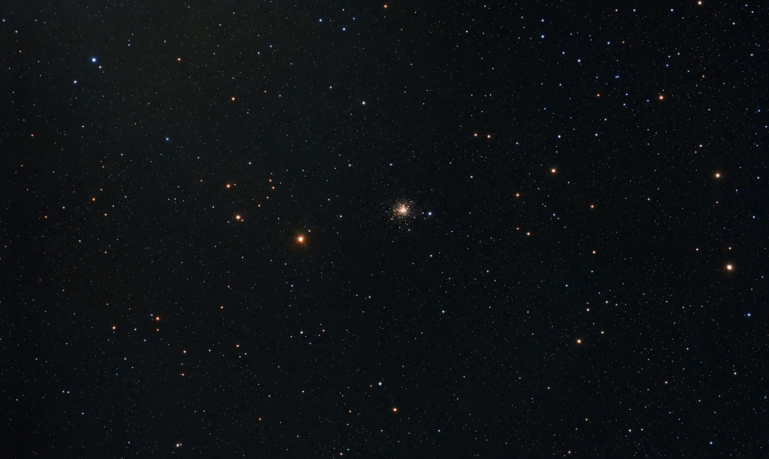 画面中心聚集着密集的恒星核，外围恒星呈放射状散开，在深空背景中展现出球状星团典型的恒星聚集结构。